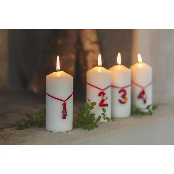 Röda adventssiffror 1–4 från Nääsgränsgården fastsatta på blockljus som står uppställda vid en öppen spis
