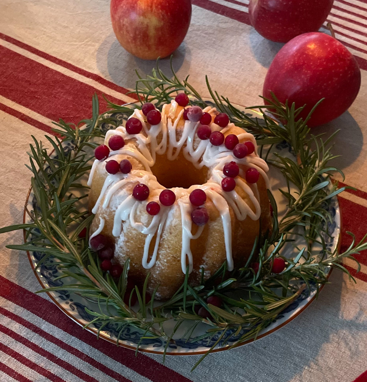 Naturfärgad bordsduk i linne och bomull med röda ränder under en juldukning med glasyrkaka och äpplen