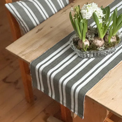 Randig bordslöpare i olivgrått och beige med vita blommor i glasskål på träbord från recycled by wille för dukning och skandinavisk inredning