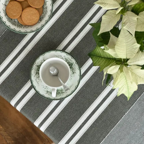 Ribbad olivgrå bordslöpare med vita ränder på dukat bord med kaffekopp och blommor från recycled by wille för skandinavisk inredning