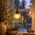 Grön fönsterlampa med klockformat räfflat glas och mässingsdetaljer samt tygsladd upphängd i ett fönster. 