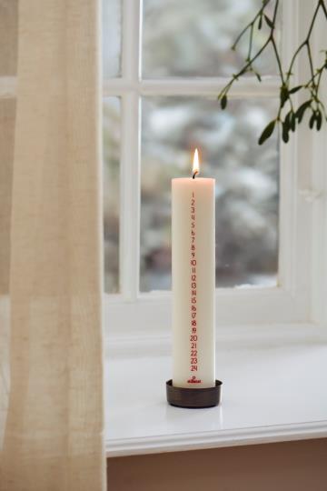 Tänt krämvitt kalenderljus med röda siffror i en stämningsfull julmiljö