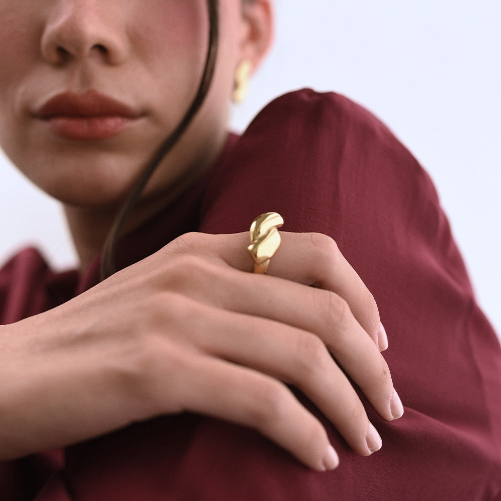 Guldpläterad ring Oria med skulptural design, buren på hand.