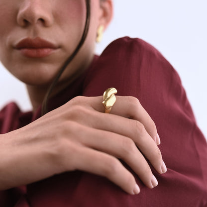 Guldpläterad ring Oria med skulptural design, buren på hand.