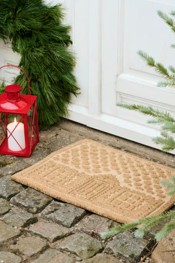 Röd jullykta med korsade spröjs placerad vid entré i julmiljö