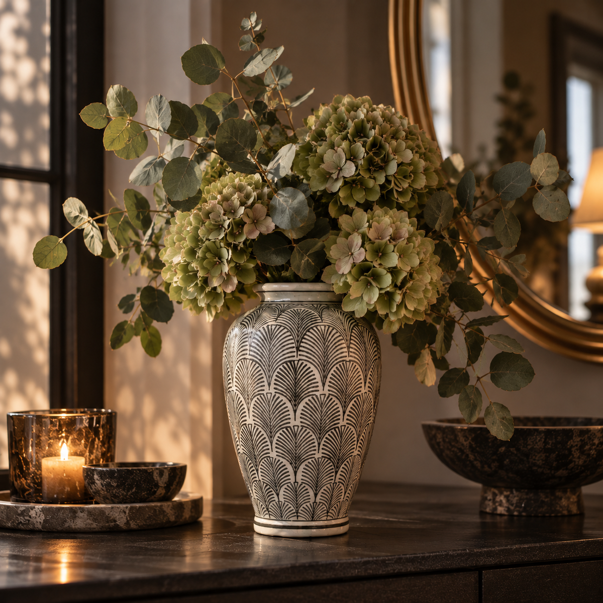 Hög svartvit keramikvas med grafiskt solfjädermönster och ett frodigt blomsterarrangemang på ett mörkt bord